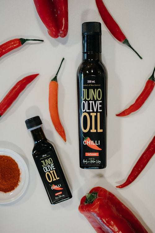 100 and 250 mL dark green bottles of Chillie Infused Olive oil. Chillies surrounding