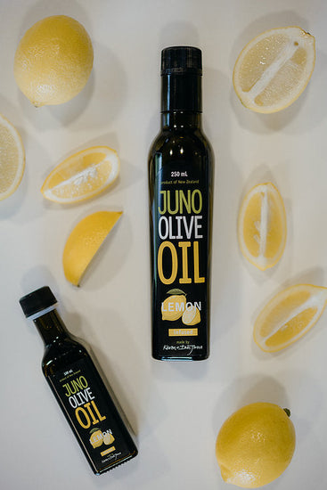 100 and 250 mL dark green bottles of Lemon Infused Olive oil. Bottles surrounded by lemons