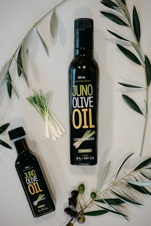 100 and 250 mL dark green bottles of Lemongrass Infused Olive oil. Lemongrass and Olive leaves surrounding