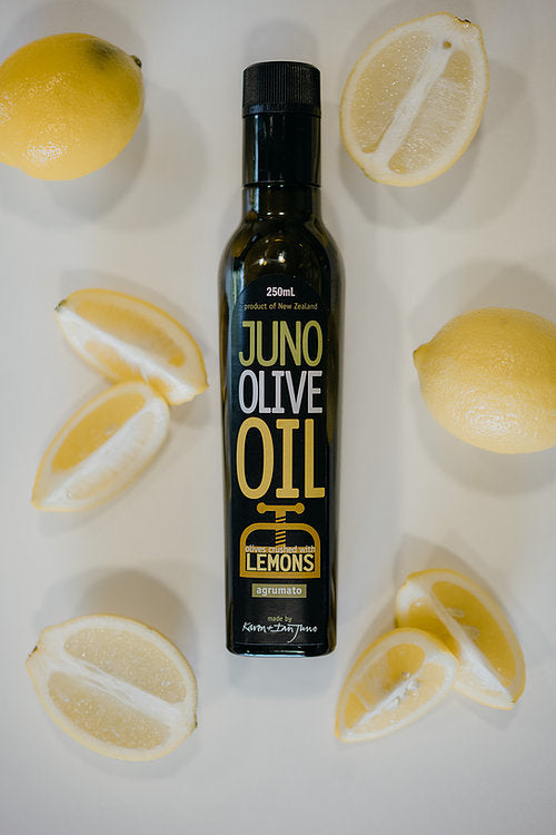 250 mL dark green bottle of Lemon agrumato oil, surrounded by Lemons.